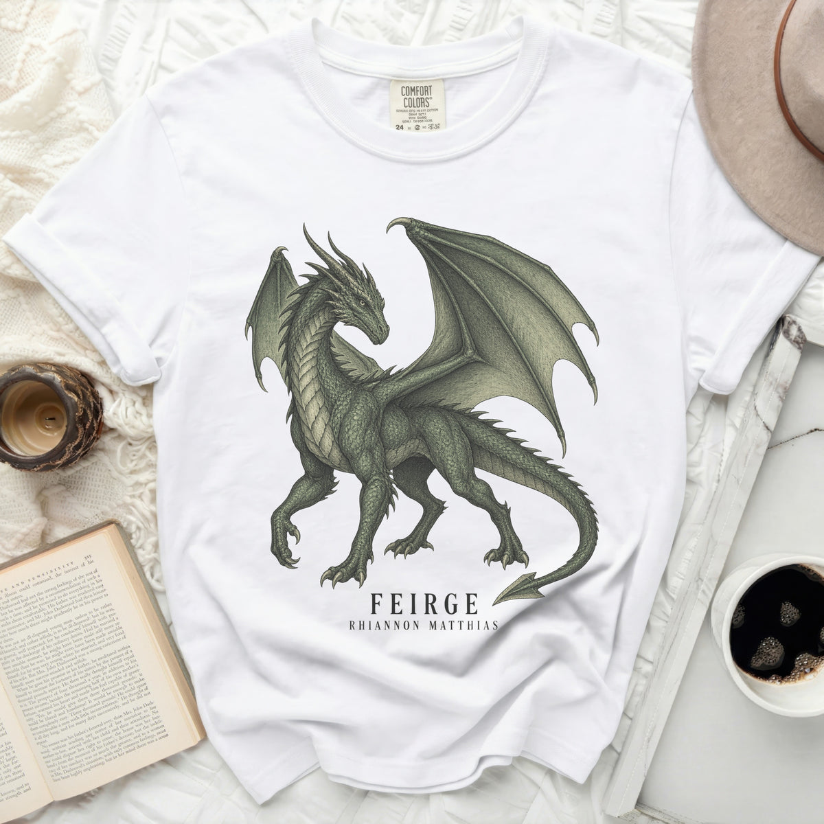 White t-shirt with a green dragon graphic and the text "FEIRGE RHIANNON MATTHIAS".