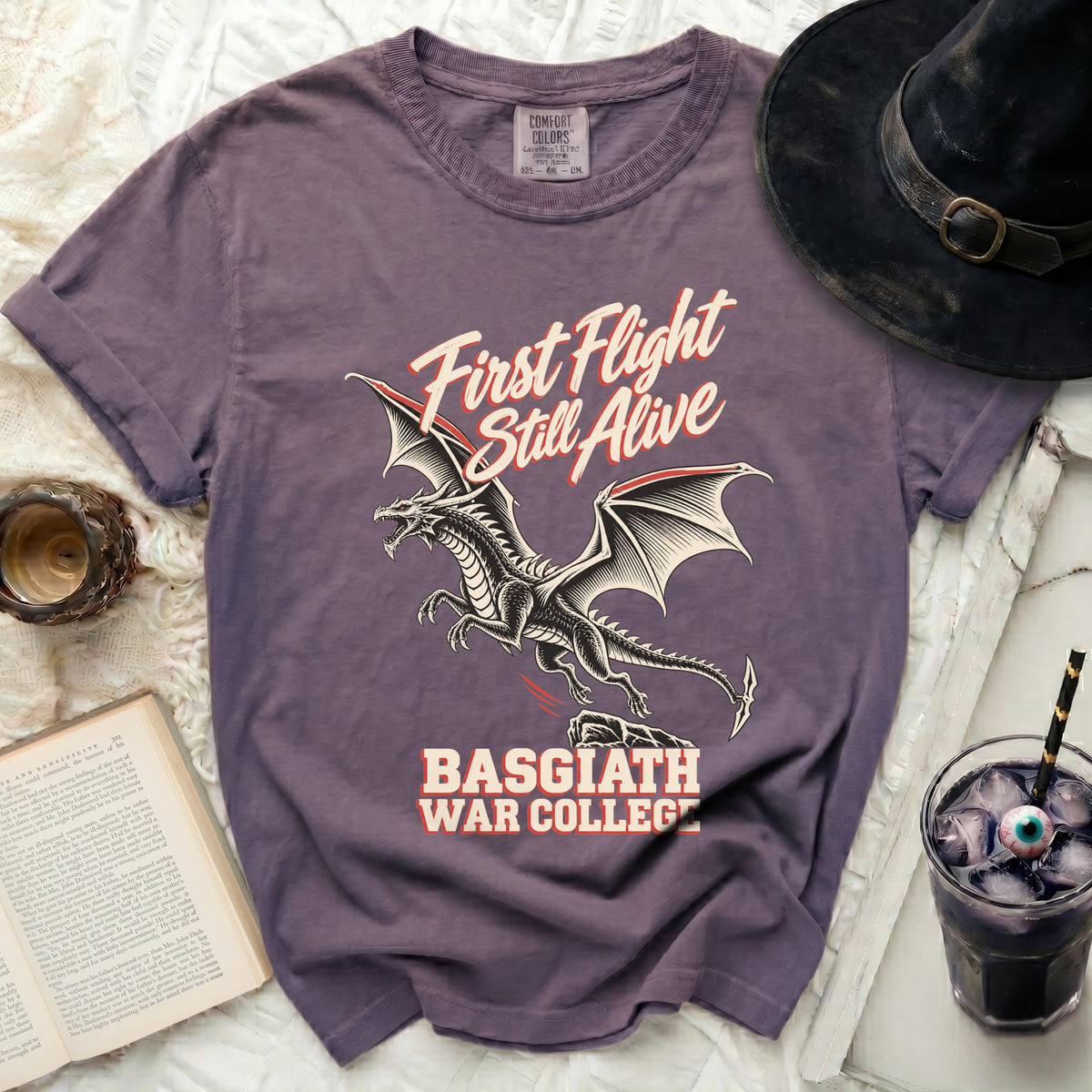Purple t-shirt with a dragon graphic and text "First Flight Still Alive" and "Basgiath War College".