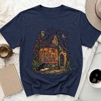 Dark navy t-shirt with a whimsical illustration of a bookish cottage at night.