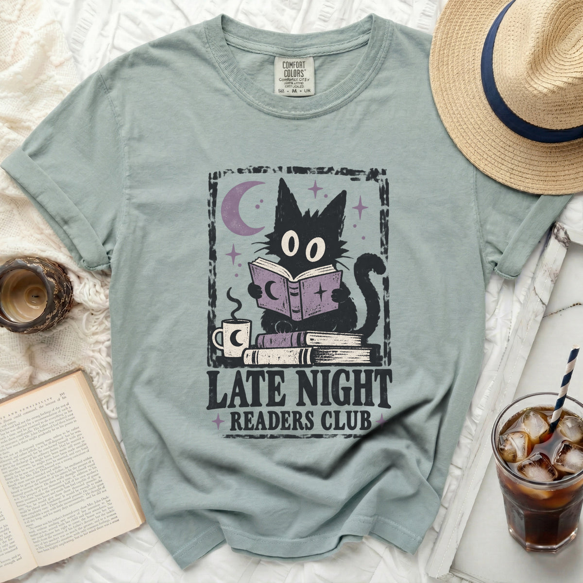 Graphic tee featuring a black cat reading under a moon, "Late Night Readers Club" text.