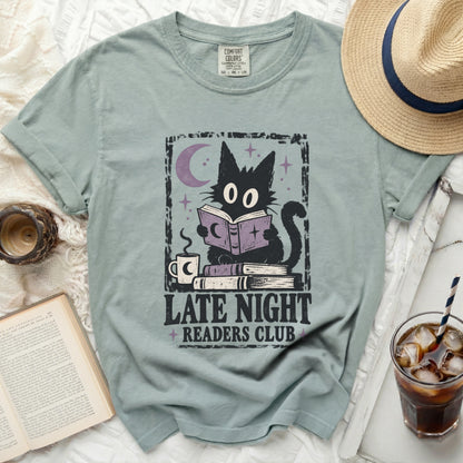 Graphic tee featuring a black cat reading under a moon, "Late Night Readers Club" text.
