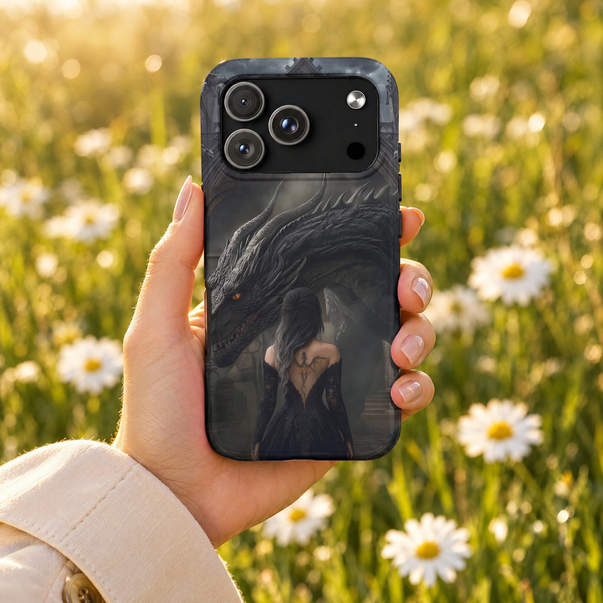 A hand holds a smartphone with a dark fantasy case featuring a dragon and woman.