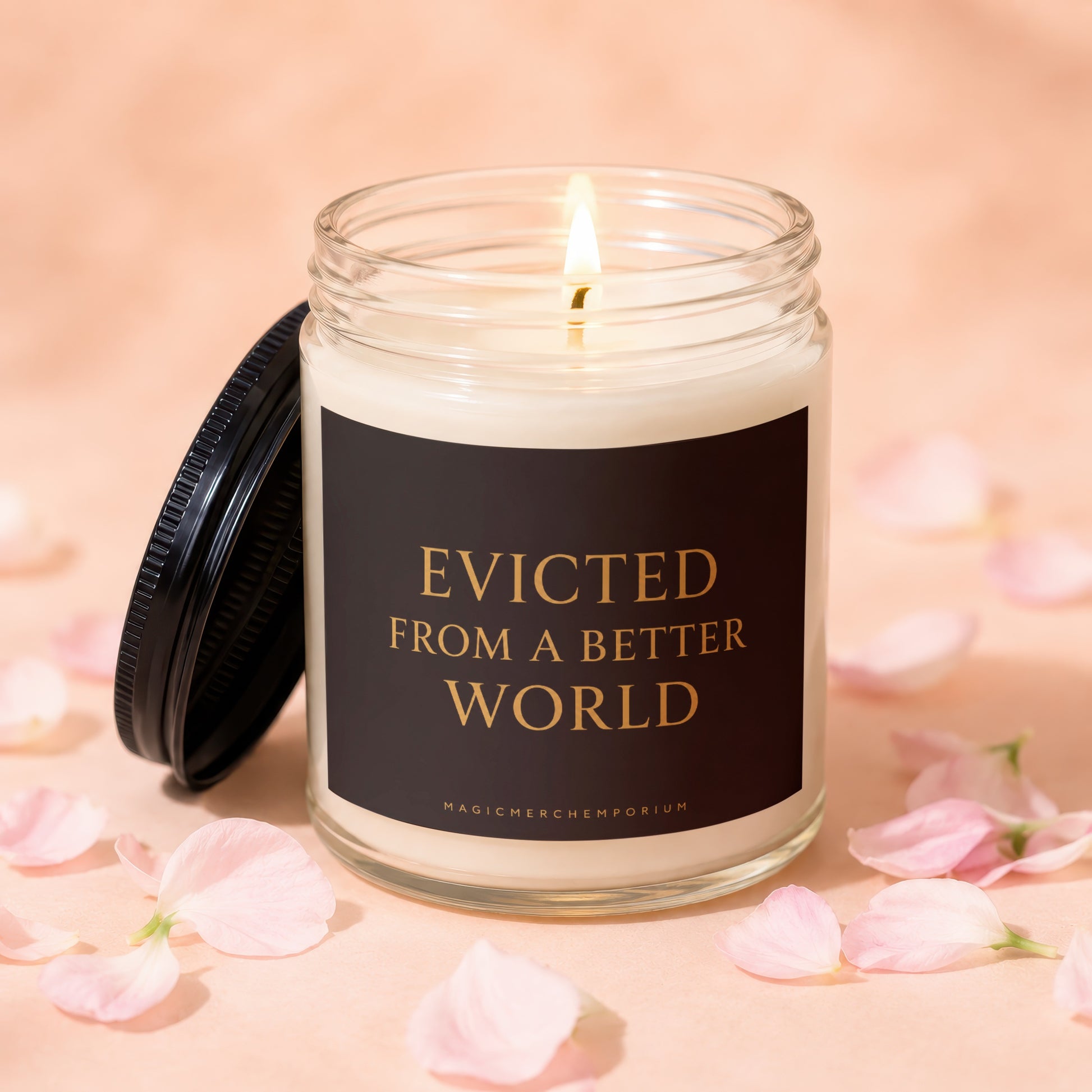 Candle with "Evicted From A Better World" on label, surrounded by pink petals.
