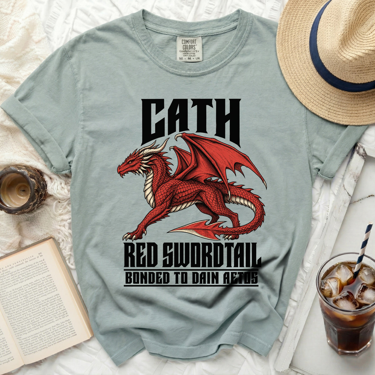 Light blue t-shirt with a red dragon graphic and text "CATH RED SWORDTAIL BONDED TO DAIN AETOS".