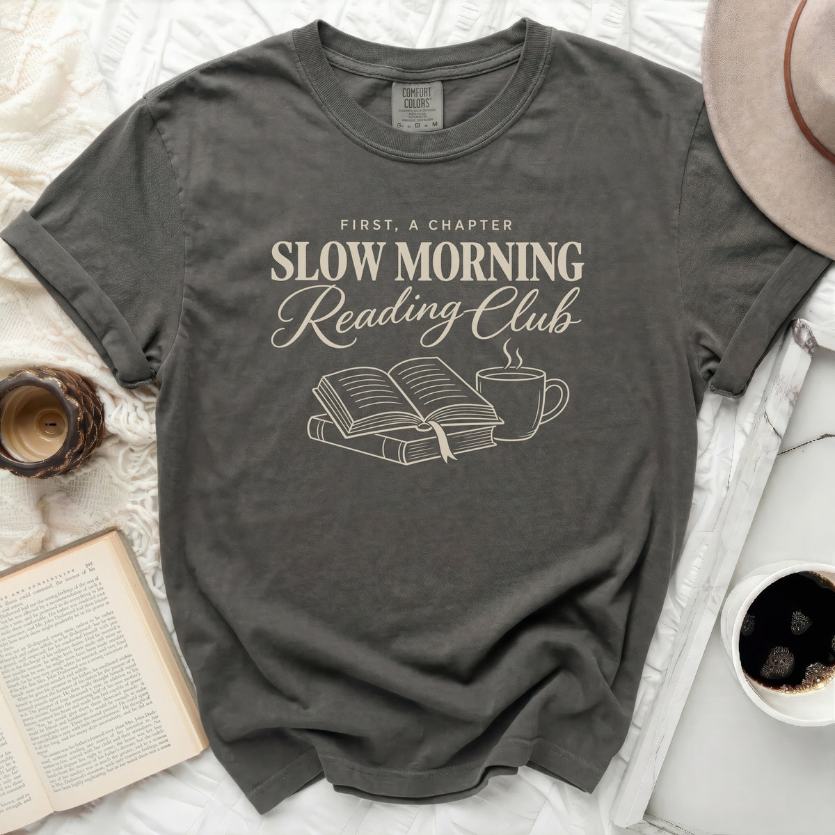 Dark gray Comfort Colors t-shirt with "First, A Chapter Slow Morning Reading Club" text and book illustration.