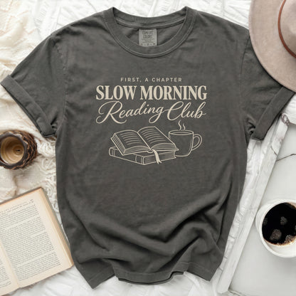 Dark gray Comfort Colors t-shirt with "First, A Chapter Slow Morning Reading Club" text and book illustration.
