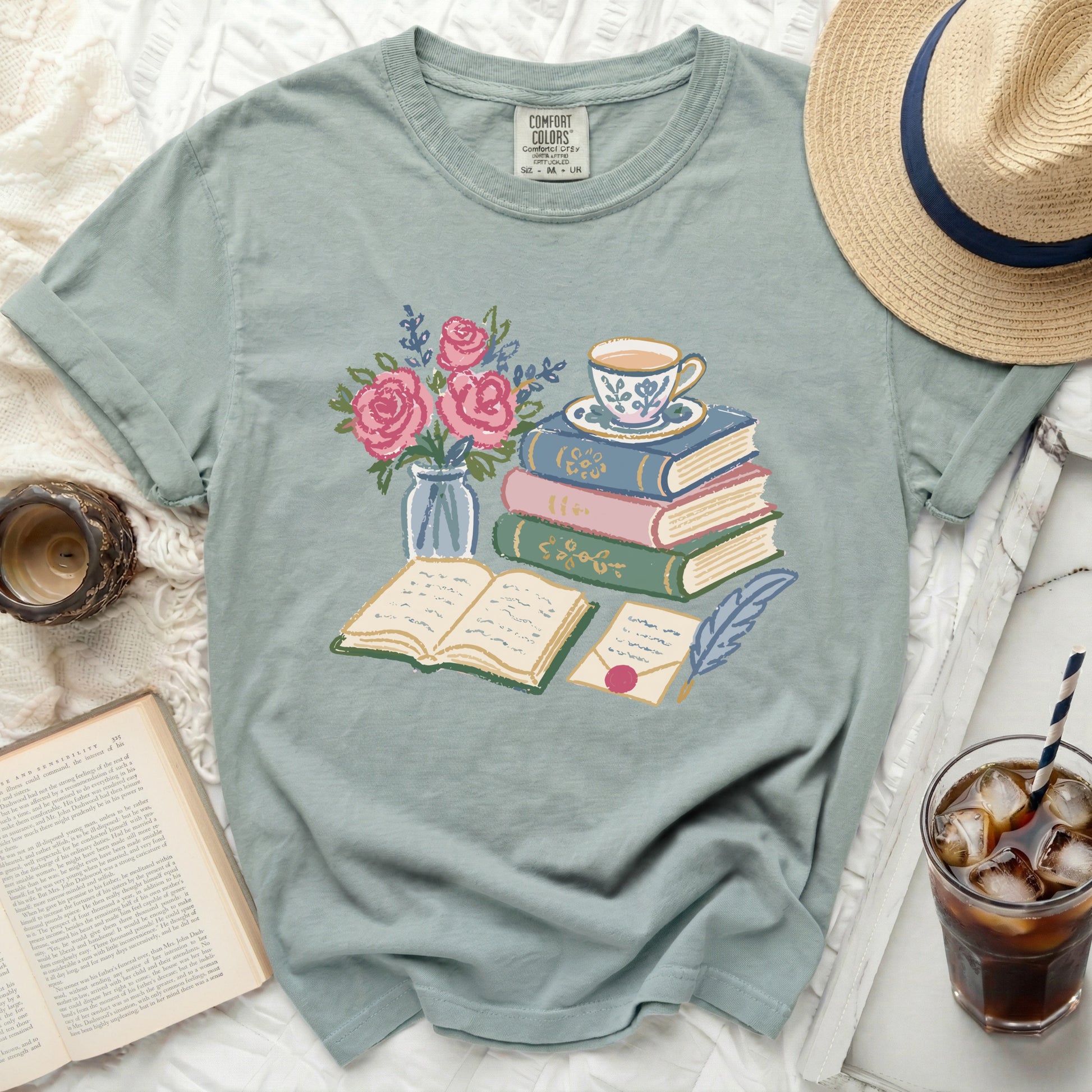 T-shirt with a print of books, a teacup, a vase of roses, and a letter.