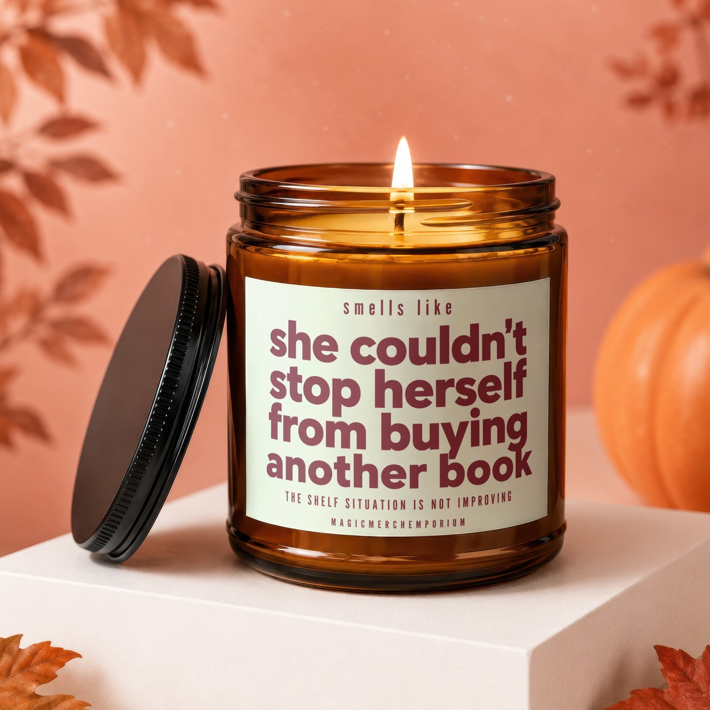 Amber jar candle lit, reading "smells like she couldn't stop herself from buying another book."