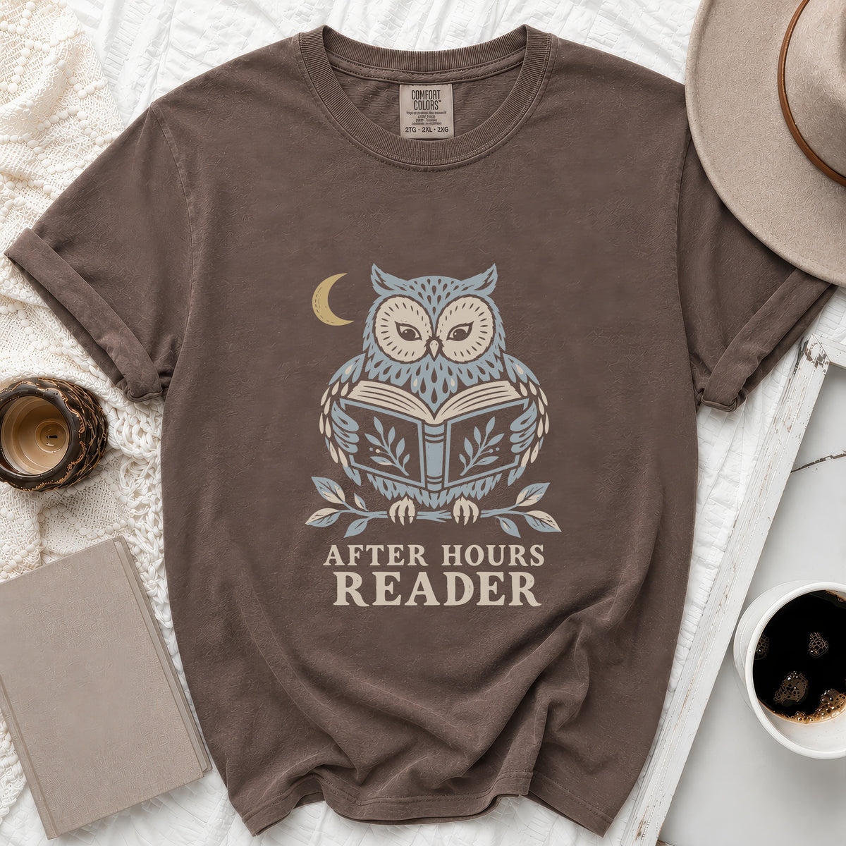 Brown t-shirt with a graphic of an owl reading a book under a moon.
