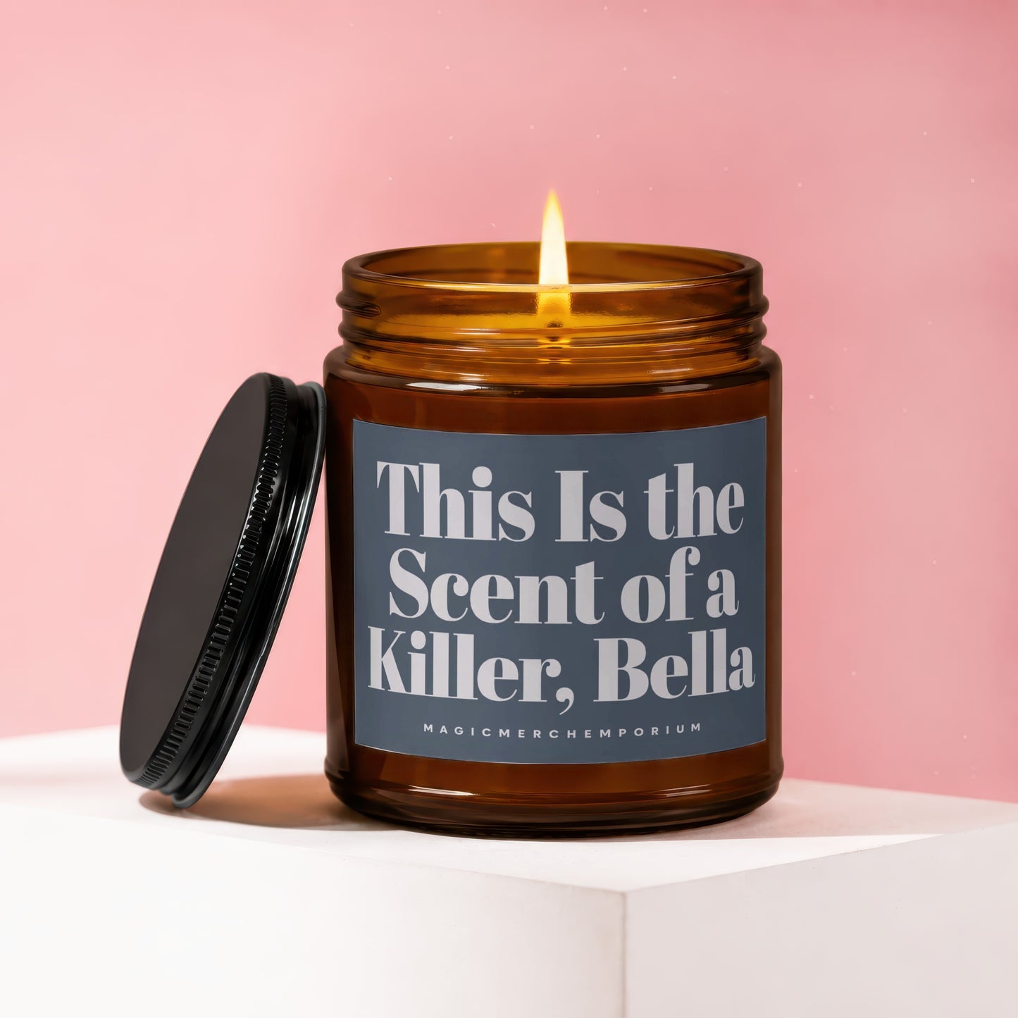 Amber jar candle with lit wick, lid off, text "This Is the Scent of a Killer, Bella".