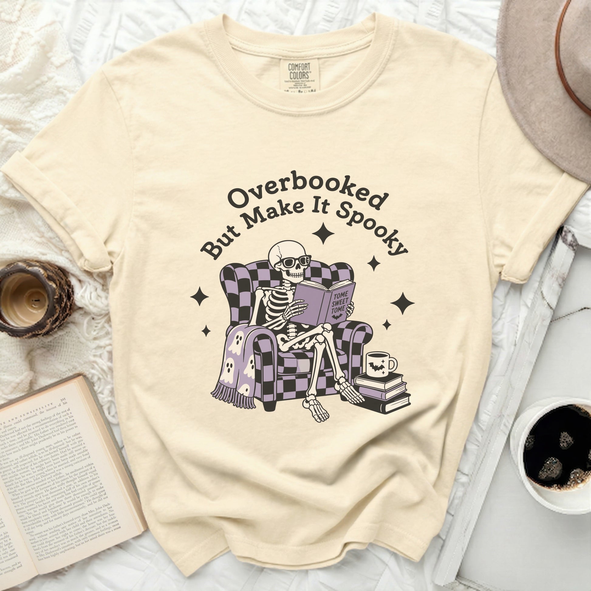 Skeleton reading a book with "Tome Sweet Tome" on cream t-shirt
