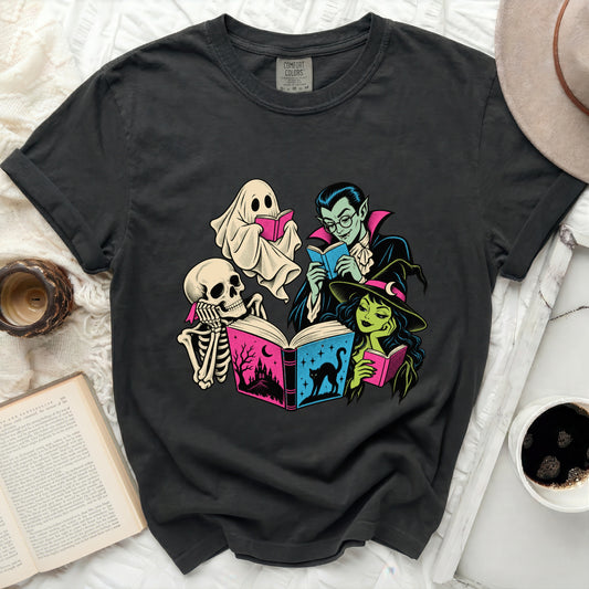 Dark gray t-shirt featuring a Halloween-themed graphic of a ghost, skeleton, vampire, and witch reading books.
