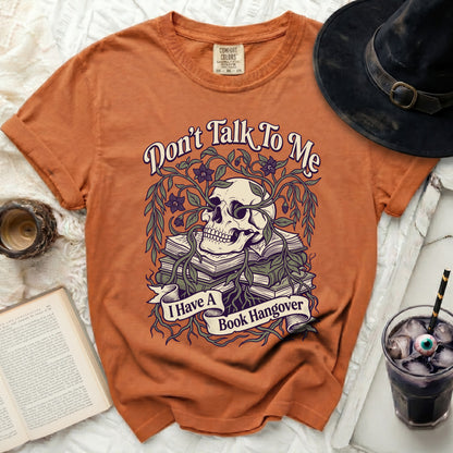 Orange t-shirt with a skull, books, and vines graphic reading "Don't Talk To Me I Have A Book Hangover".