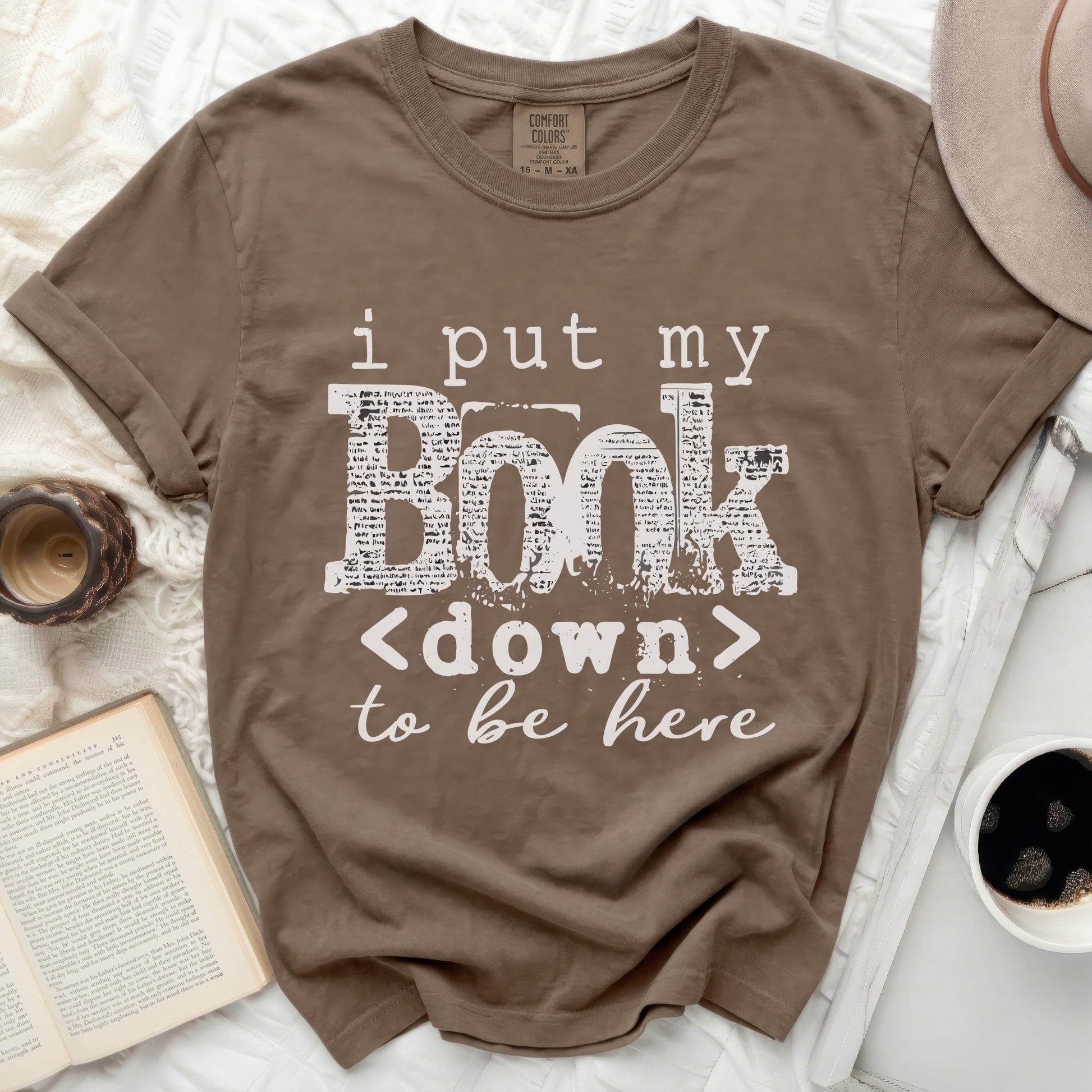 Brown t-shirt with "i put my book <down> to be here" text.