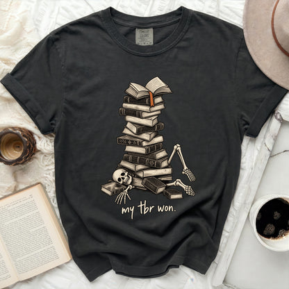 Dark grey t-shirt with skeleton buried under books and text "my tbr won."