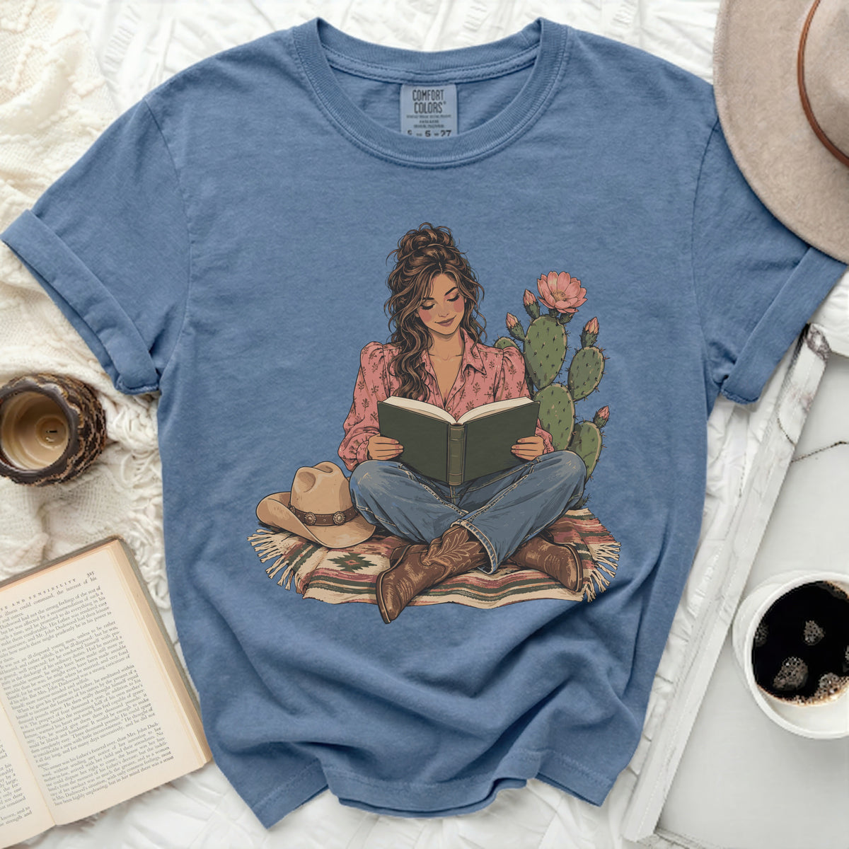 Graphic of woman reading with cowboy hat, boots, cactus, and patterned blanket.