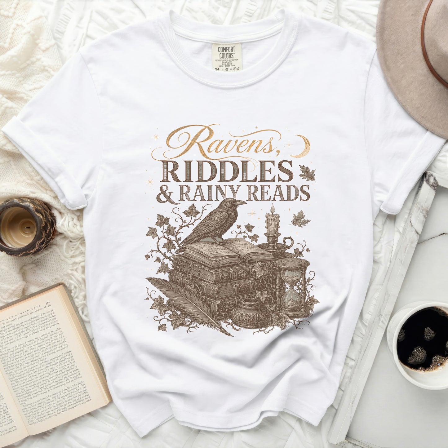 White t-shirt with "Ravens, Riddles & Rainy Reads" graphic.