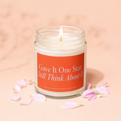 Lit candle in jar with orange label reading "Gave It One Star. Still Think About It."
