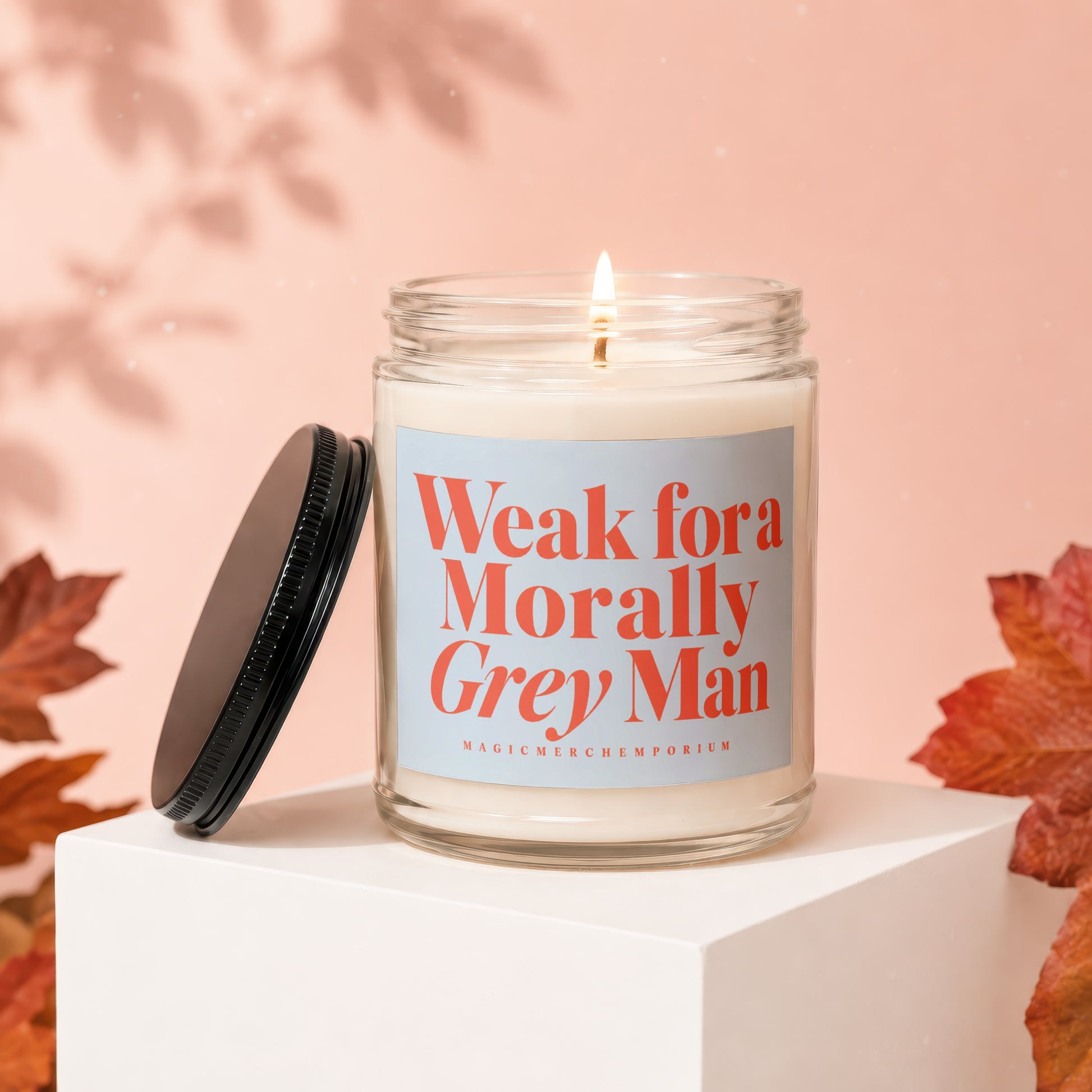 Candle with lit wick and black lid, labeled "Weak for a Morally Grey Man."