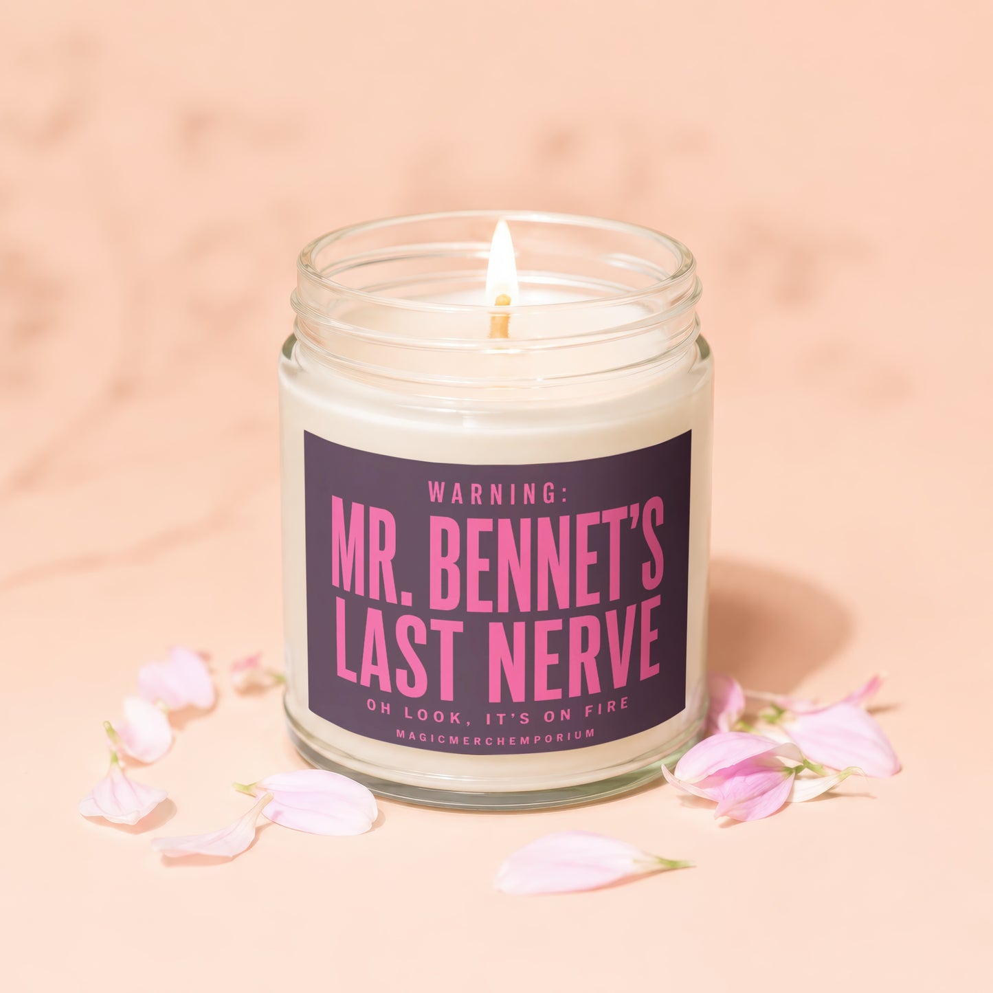Lit candle in glass jar with "Mr. Bennet's Last Nerve" text and pink petals.