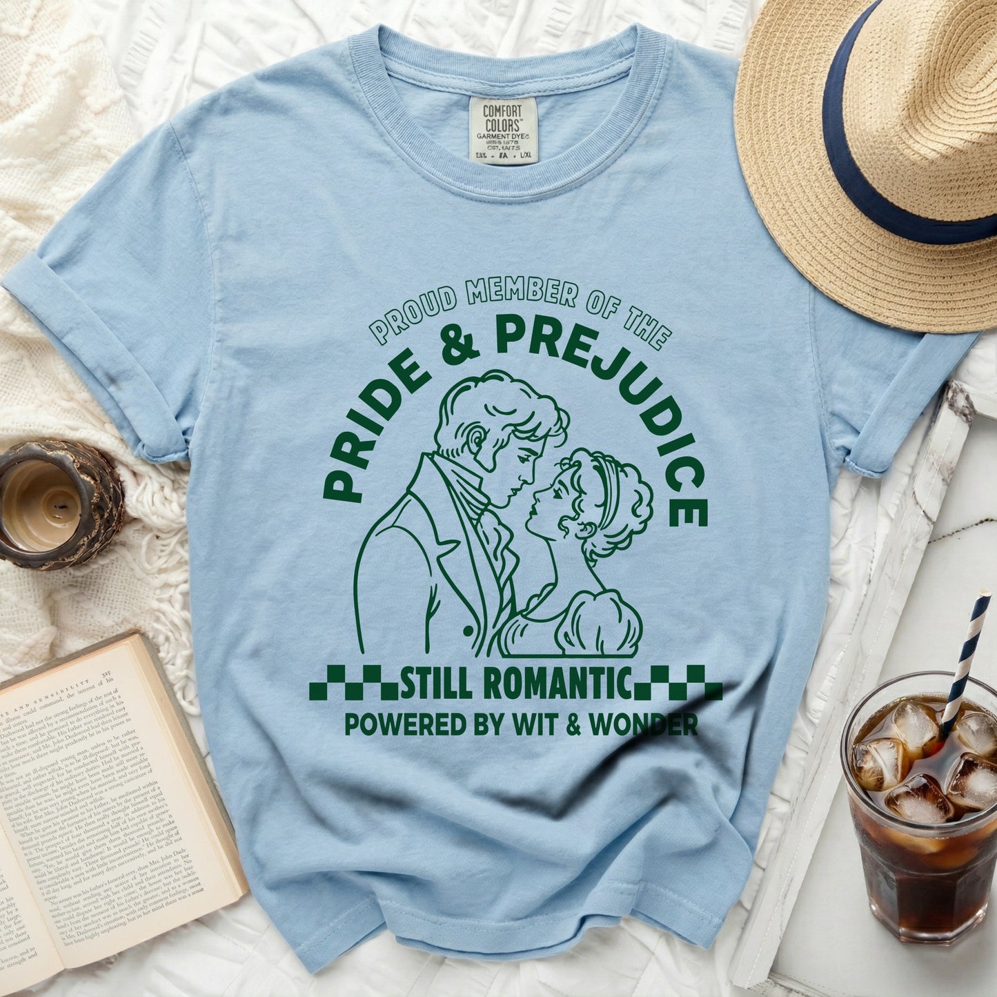 Light blue t-shirt with "Pride & Prejudice Still Romantic Powered by Wit & Wonder" graphic.