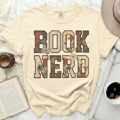 Cream t-shirt with "BOOK NERD" text filled with floral illustrations and a butterfly.