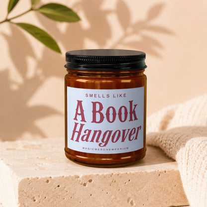 Amber jar candle with "Smells Like A Book Hangover" text with "MagicMerchEmporium" beneath.