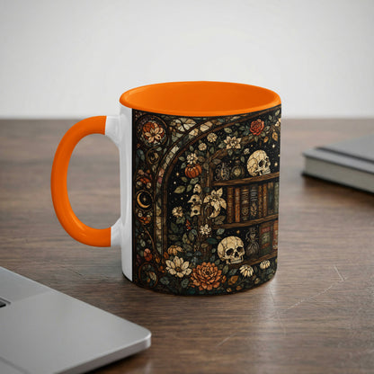 White mug with orange handle featuring a dark, stained-glass style design of books, skulls, and flowers.