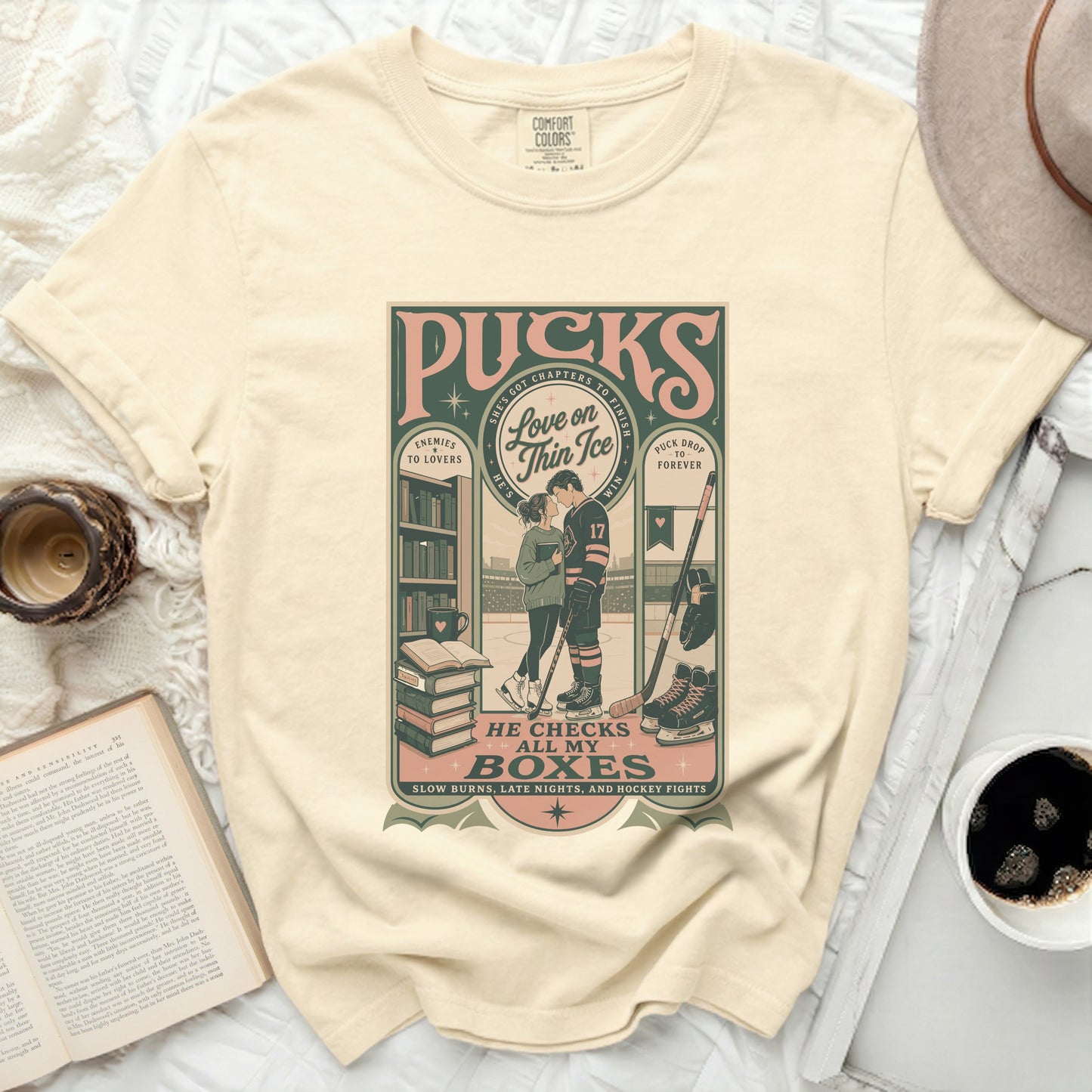 Cream t-shirt with "Puck Drop" graphic featuring hockey player and books.