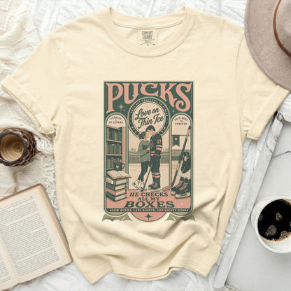 Cream t-shirt with "Puck Drop" graphic featuring hockey player and books.