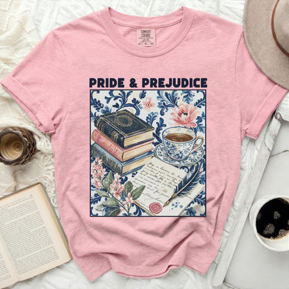 Pink t-shirt with "Pride & Prejudice" text and a vintage book stack, teacup, quill, and floral print.