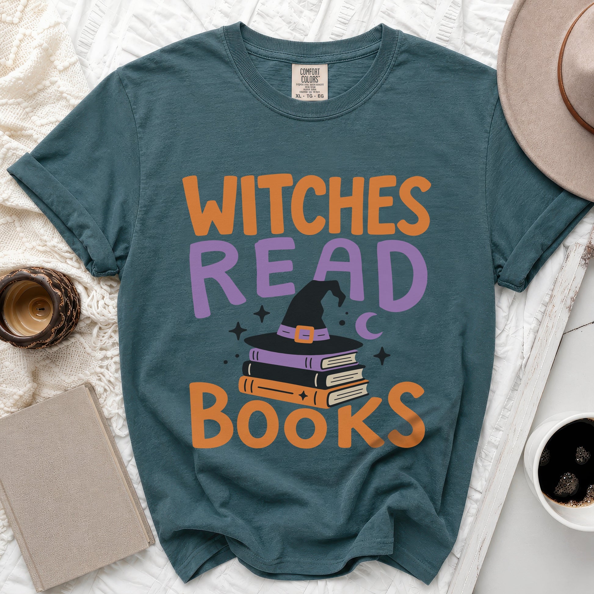 Teal t-shirt with "Witches Read Books" text, witch hat, and stacked books.