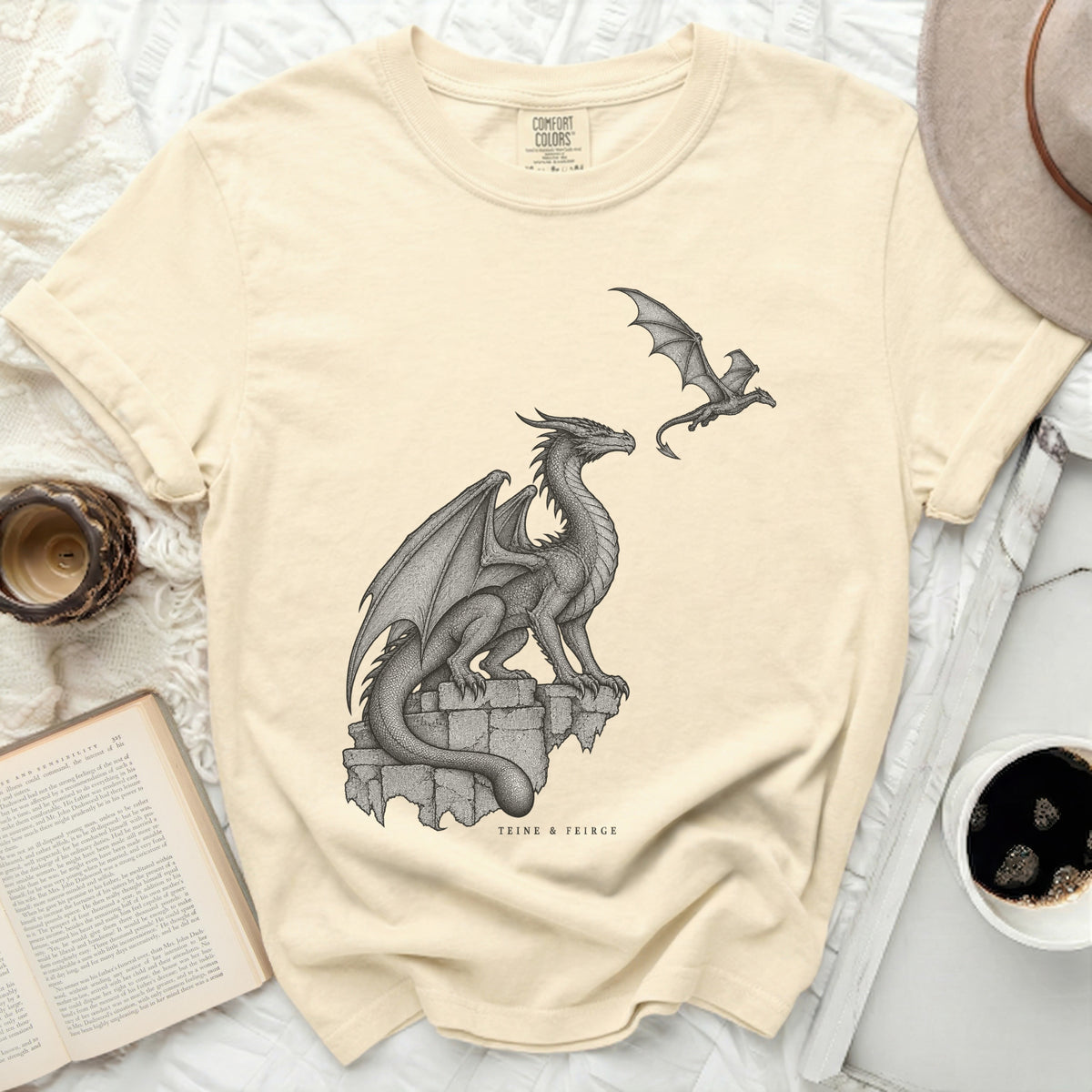 Cream t-shirt with a large dragon perched on stones and a smaller dragon flying.