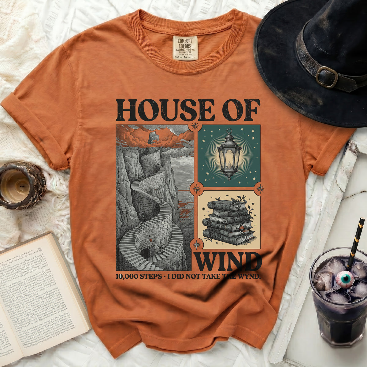 Orange t-shirt with "House of Wind" graphic, a winding staircase, and books.