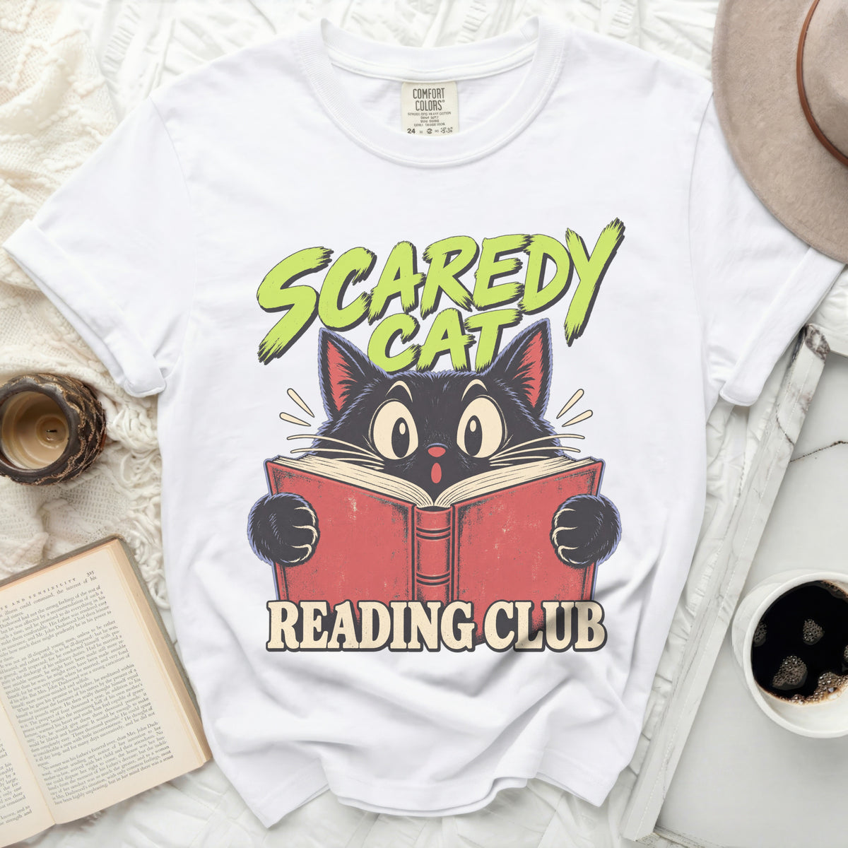 White t-shirt with a cartoon black cat reading a book, "Scaredy Cat Reading Club" text.