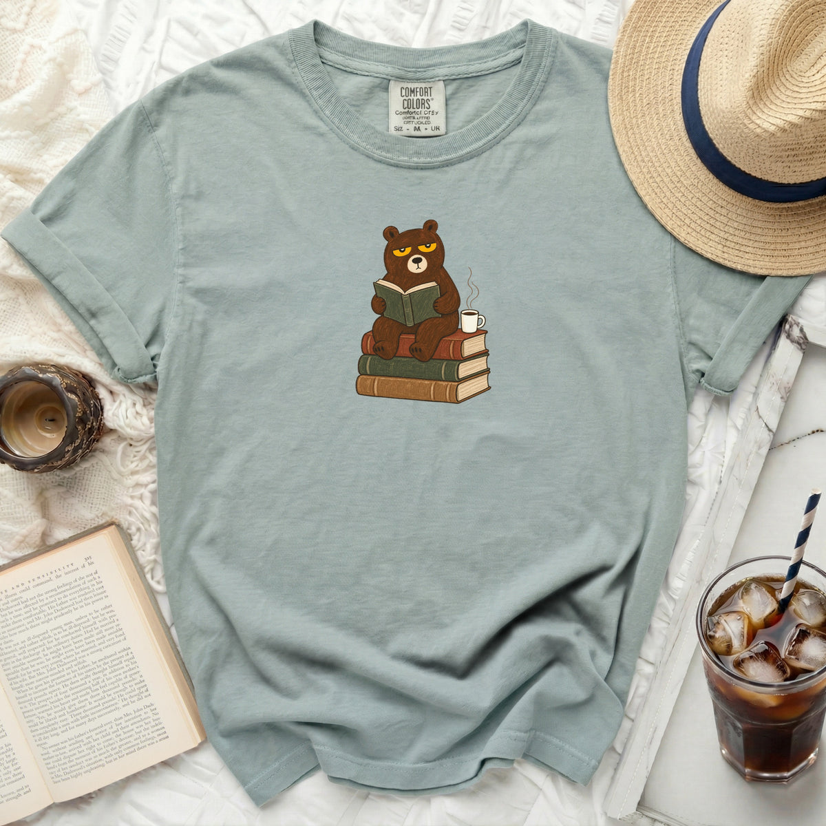 T-shirt with a graphic of a grumpy bear reading a book on stacked books.