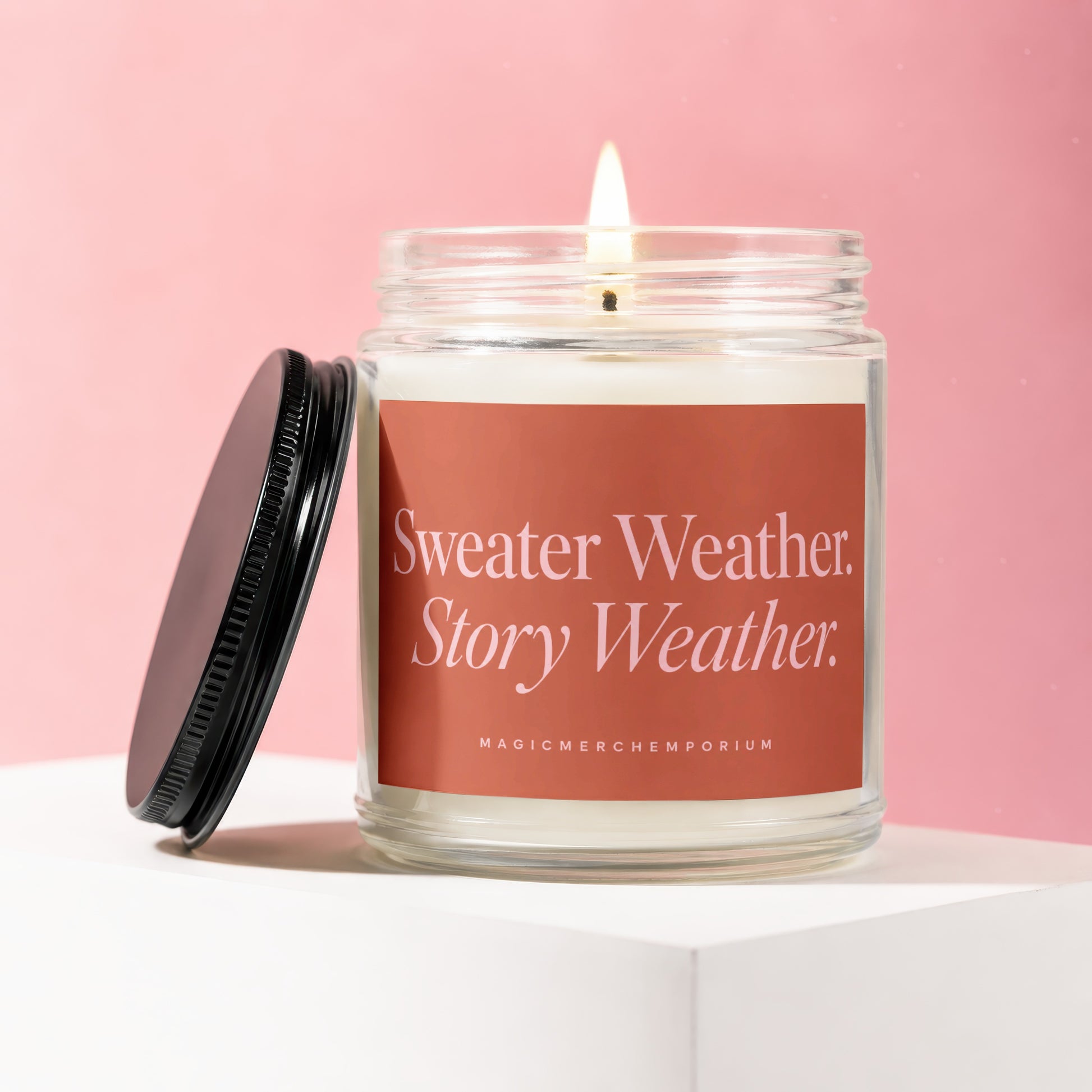 Candle with a lit wick and "Sweater Weather. Story Weather." label on pink background.