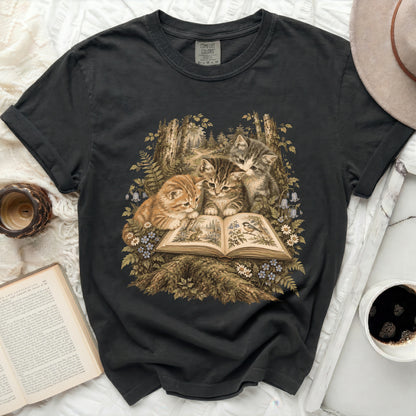 Black t-shirt with three kittens reading an open book in a forest.
