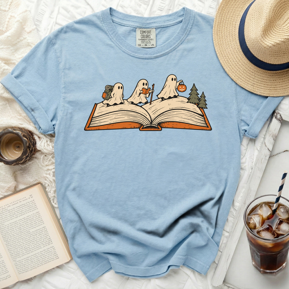 Light blue t-shirt with ghosts reading and trick-or-treating on an open book.