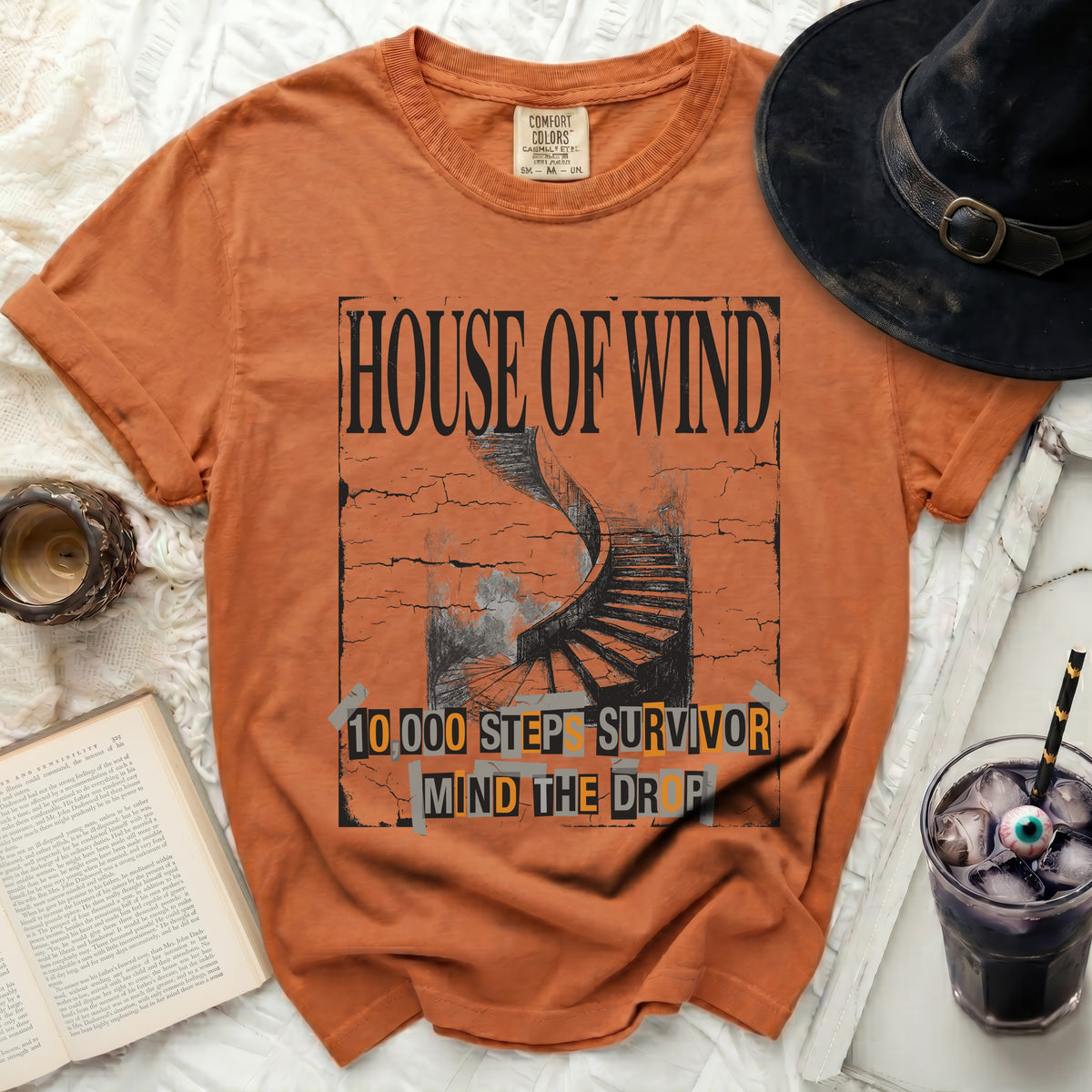 Orange t-shirt with "HOUSE OF WIND" and "10,000 STEPS SURVIVOR MIND THE DROP" text.