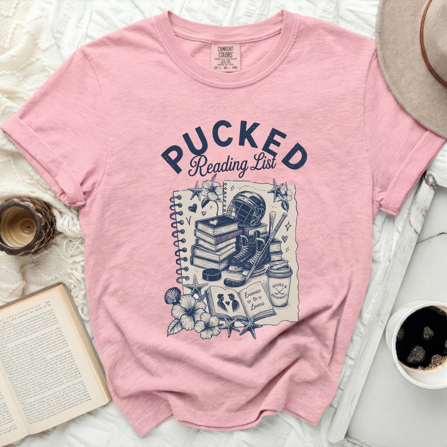 Pink t-shirt with "Pucked Reading List" and hockey gear illustration.