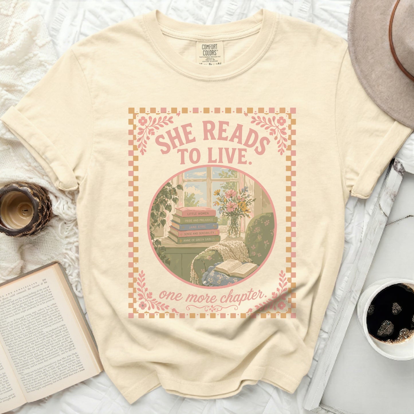 Cream t-shirt with "She Reads to Live. One More Chapter." book illustration.