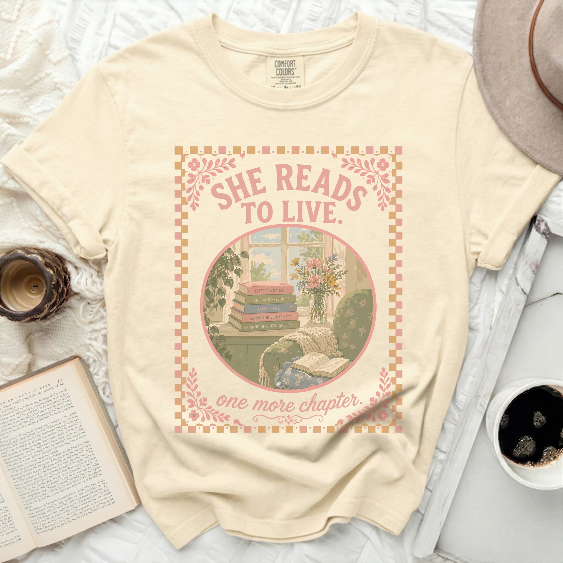Cream t-shirt with "She Reads to Live. One More Chapter." book illustration.