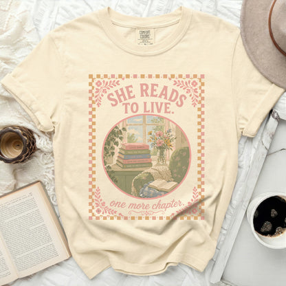 Cream t-shirt with "She Reads to Live. One More Chapter." book illustration.