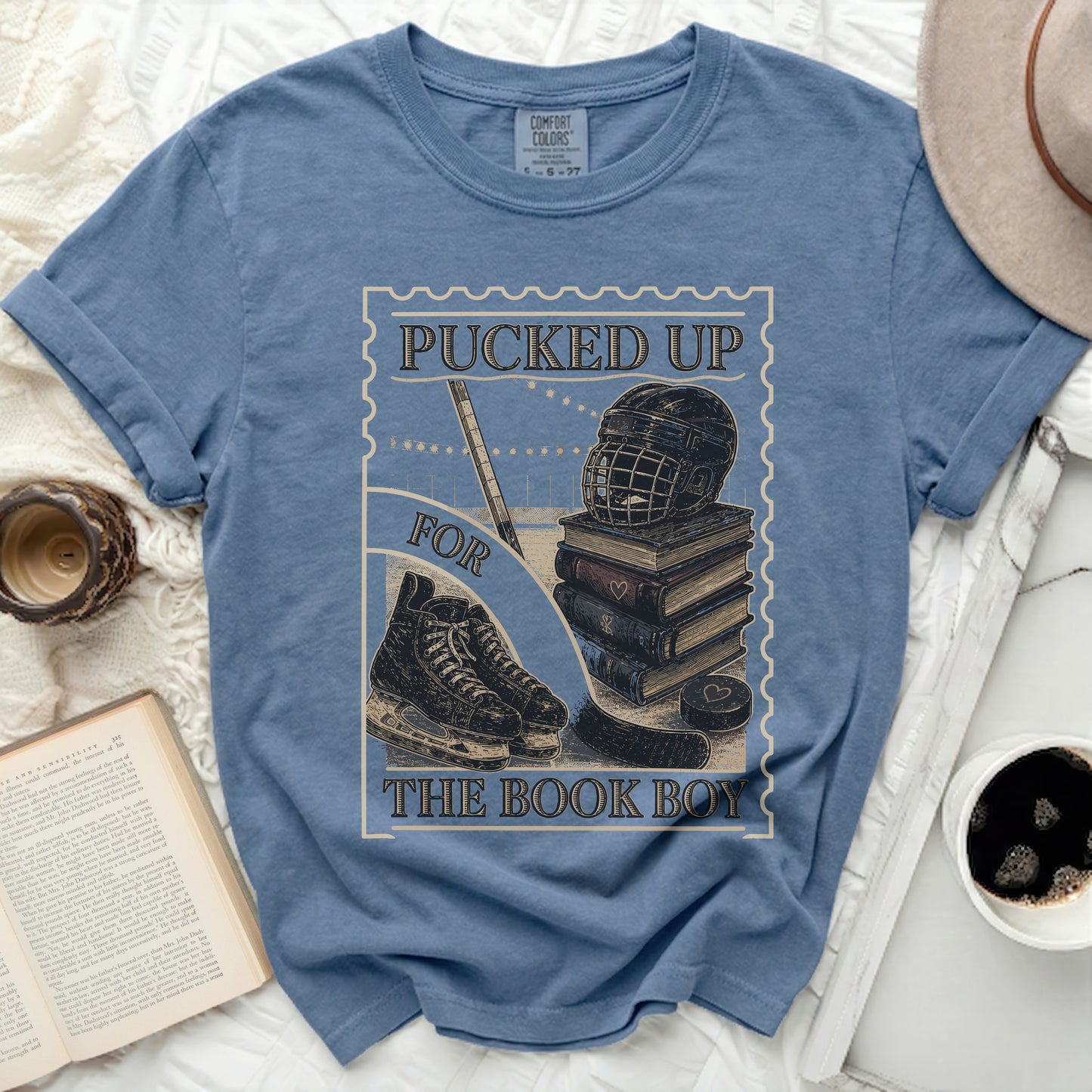 Blue t-shirt with hockey gear and books, reads "Pucked Up The Book Boy."