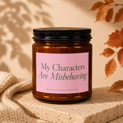 Amber glass candle with a pink label that reads "My Characters Are Misbehaving."