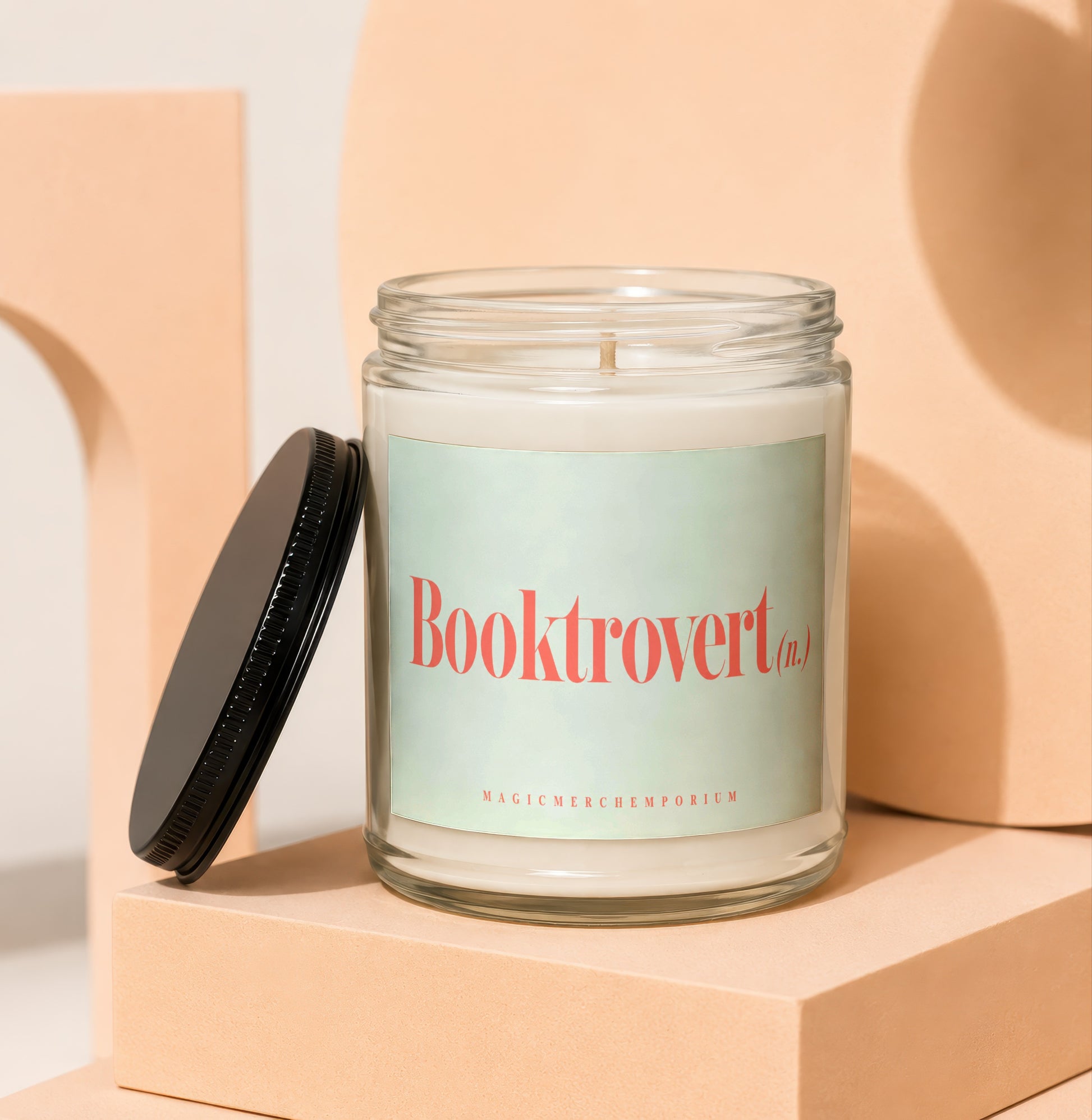Glass candle with "Booktrovert (n.)" text and "MAGICMERCH`EMPORIUM" below.