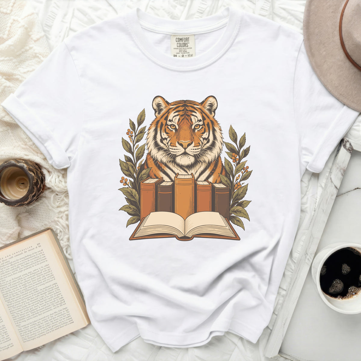 White t-shirt with a graphic of a tiger head behind books and greenery.