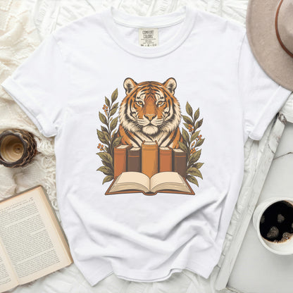 White t-shirt with a graphic of a tiger head behind books and greenery.