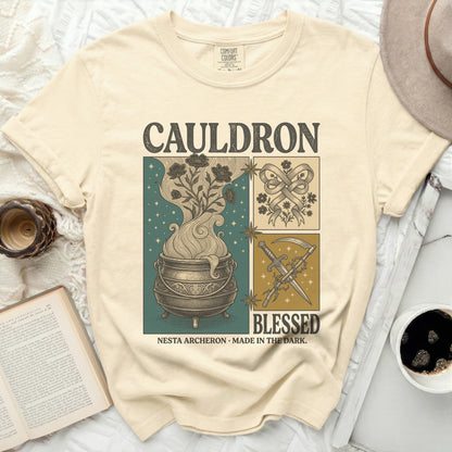 Cream t-shirt with "CAULDRON", "BLESSED", "NESTA ARCHERON", and "MADE IN THE DARK" text and illustrations.